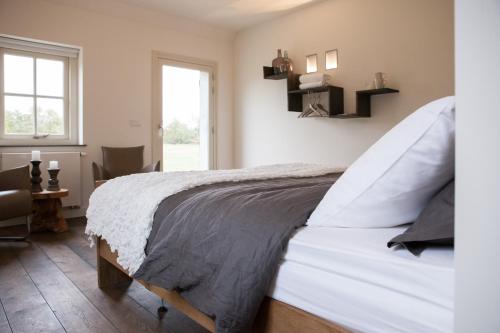 a bedroom with a large white bed with a window at Gasterij Landschot in Hoogeloon