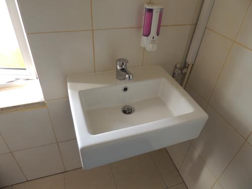 a white sink in a white tiled bathroom at Delphi Hotel in Nicosia