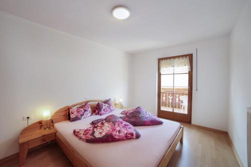 a bedroom with a bed with purple pillows and a window at Strickerhof - Appartment 2 in Saltusio