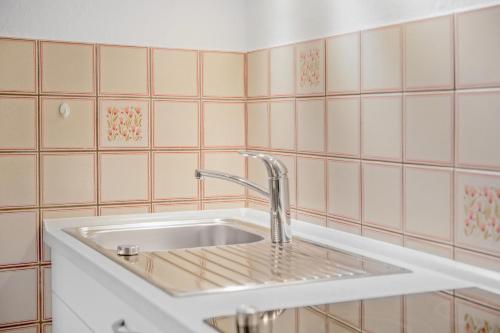 um lavatório numa casa de banho com azulejos cor-de-rosa em Ferienwohnung Wennesz 2 em Chieming
