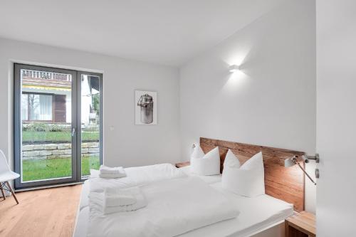 a white bedroom with a large bed with white pillows at Ferienhaus Seebruck in Seebruck