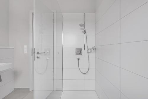 a white bathroom with a shower with a glass door at Ferienhaus Seebruck in Seebruck