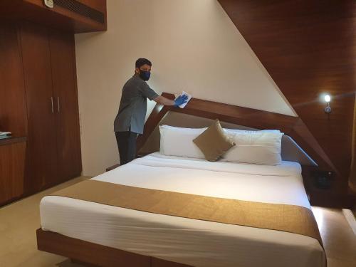 a man in a mask standing next to a bed at Dragonfly Hotel - The Art Hotel in Mumbai