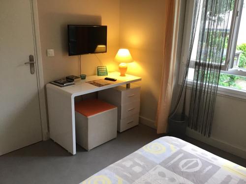 - une chambre avec un bureau, une télévision et un lit dans l'établissement Le Clos Doménat 2, à Brive-la-Gaillarde