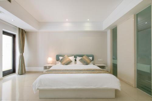 a bedroom with a large white bed with pillows at Sanya Sun and Sea Gueshouse in Sanya
