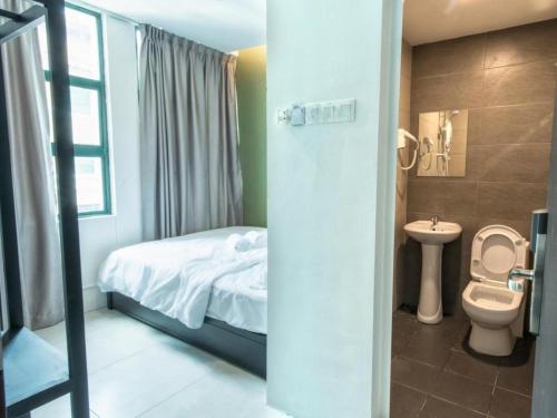 a bathroom with a bed and a toilet and a sink at Econtel Queensbay in Bayan Lepas