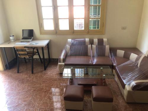 Una sala de estar con un sofá y un escritorio con una computadora portátil. en Green Homestay, en Hanói