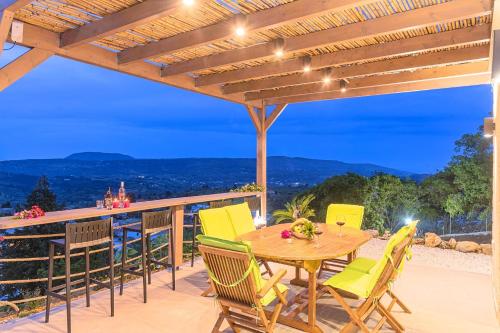 a patio with a wooden table and chairs on a deck at Villa Vardis Heated Pool in Vryses