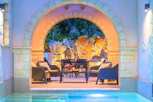Villa Vardis Heated Pool في Vryses: غرفة مع طاولة وكراسي ومسبح