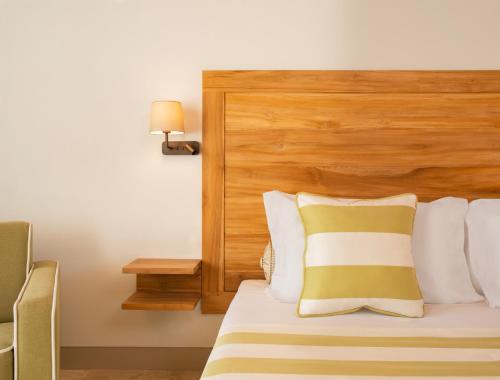 ein Hotelzimmer mit einem Bett mit einem Kopfteil aus Holz in der Unterkunft San Michele Relais & Spa in Sirolo