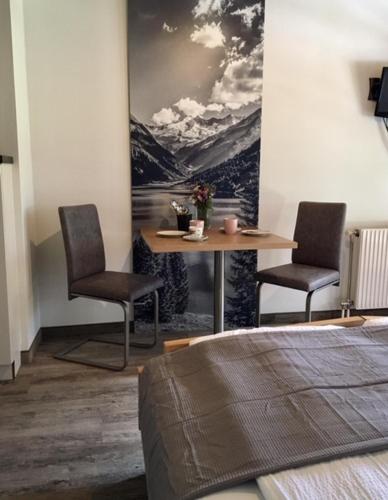 a room with two chairs and a table with a painting at Landhaus Rosengartl Krimml in Oberkrimml