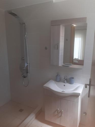 uma casa de banho branca com um lavatório e um chuveiro em Aegean View Villa em Loutraki