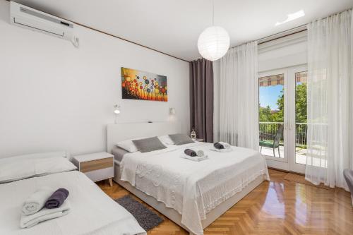 biała sypialnia z 2 łóżkami i oknem w obiekcie Apartments Rosovic J&C w mieście Mošćenička Draga