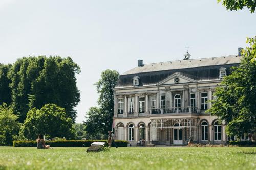 a woman sitting on the grass in front of a house at Buitenplaats Vaeshartelt in Maastricht