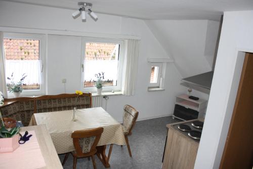 a kitchen with a table and chairs and two windows at Heidezeit - Ferienwohnungen in Müden in Faßberg