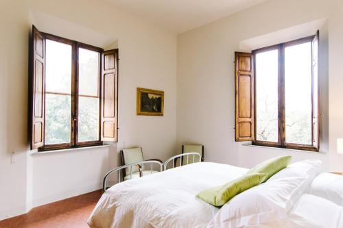 a white bedroom with windows and a bed at Tenuta Santa Trice in Riotorto