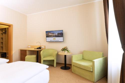 a room with a bed and two chairs and a desk at Hotel Česká Koruna in Děčín