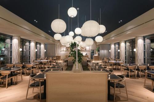 a dining room with tables and chairs and chandeliers at Vaeshartelt Maastricht in Maastricht