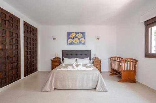 een witte slaapkamer met een bed en 2 stoelen bij Nerja Capistrano Villa in Nerja