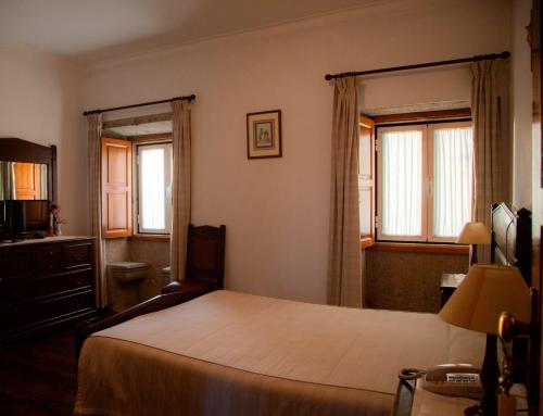 um quarto com uma cama grande e 2 janelas em Quinta de São Bento em Vila de Prado