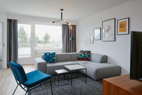 a living room with a couch and a blue chair at Welcome in - Modernes Apartment 70-MA in der Nähe der Skipiste in Winterberg