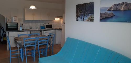 une cuisine avec des chaises bleues et une table dans l'établissement Porteo - Les Terrasses du Port, à Centuri