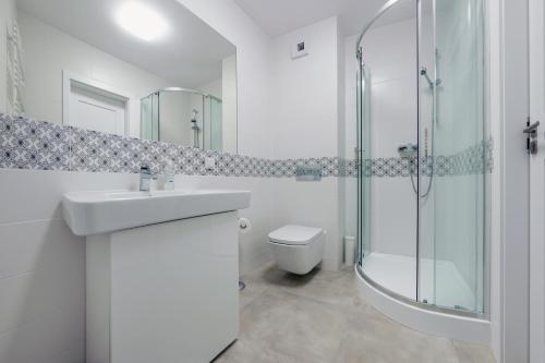 a bathroom with a sink and a shower and a toilet at Rezydencja Park, Sun & Snow in Mielno