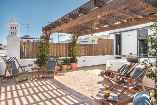 a patio with chairs and a wooden pergola at Lemon Tree Stay in Faro