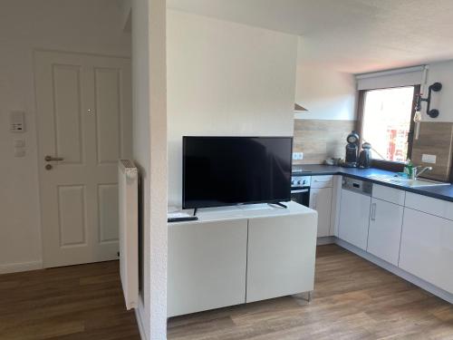 a kitchen with a flat screen tv on a white cabinet at holiday-apartments in Bremen