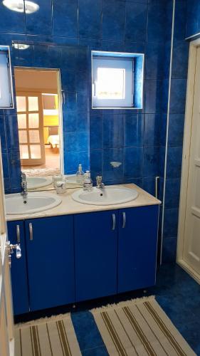 a blue bathroom with two sinks and a mirror at Lend two room house in Miercurea-Ciuc