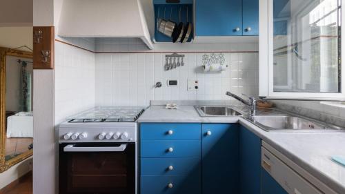 cocina con armarios azules, fogones y fregadero en Italianway - Fontanelle 34, en Alassio