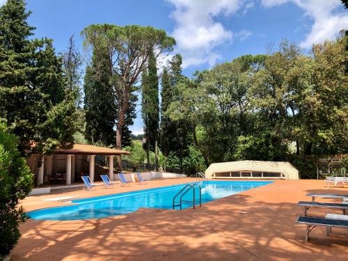 a large swimming pool with lounge chairs and trees at VdP Luxury Tuscan Villa in San Baronto