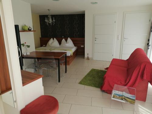 a living room with a bed and a red couch at Gartenappartement Ybbs in Ybbs an der Donau