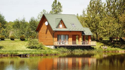 a wooden house with a balcony next to a lake at Shepilska Relax Complex in Dovholuka
