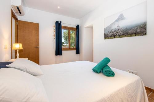 ein Schlafzimmer mit einem weißen Bett und einem grünen Handtuch darauf in der Unterkunft Finca can Jaumi By homevillas360 in Artá