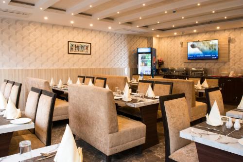a restaurant with tables and chairs and a television at Stayotel Kolkata Airport in Kolkata