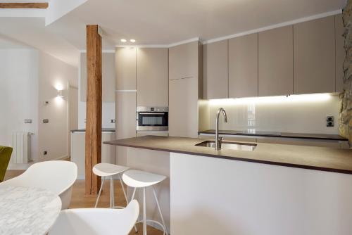 a kitchen with white cabinets and white stools at Salamanka by FeelFree Rentals in San Sebastián