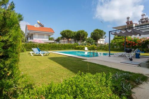 a backyard with a swimming pool and a house at EV Apartments in Belek