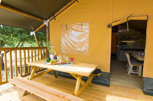 uma mesa de madeira no convés de uma casa em Grande Glamping with Pool em Biograd na Moru