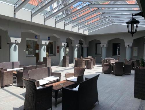 eine Terrasse mit Tischen und Stühlen in einem Gebäude in der Unterkunft Hotel Zodiaco in Szekszárd