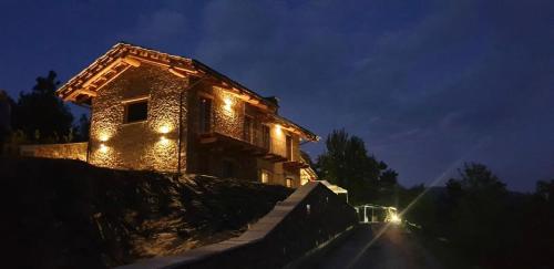 a house with lights on the side of it at night at LA DRIT in Paesana