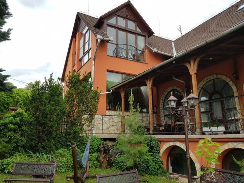una casa naranja con dos bancos delante de ella en Legányi Apartmanház, en Eger