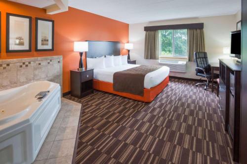a hotel room with a bed and a bath tub at AmericInn by Wyndham Sartell in Sartell