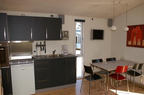 een keuken met zwarte kasten en een tafel met stoelen bij Fjordlyst Camping & Cottages in Aabenraa