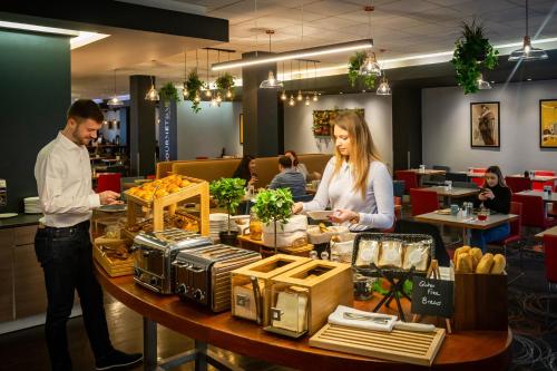 a man and woman standing at a table in a restaurant at Novotel Reading Centre in Reading
