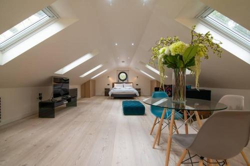 a large attic living room with a bed and a table at Luxury Coach house next to woodland in Knutsford in Knutsford