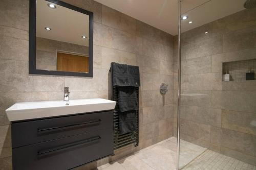 a bathroom with a sink and a shower at Luxury Coach house next to woodland in Knutsford in Knutsford