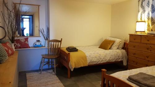a bedroom with a bed and a chair and a dresser at Woodford Guest House in old farm in Killarney