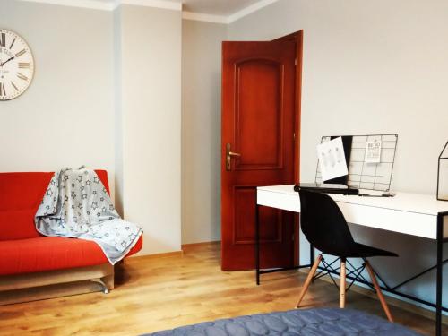 a living room with a red couch and a desk at Domek w dolinie in Berest