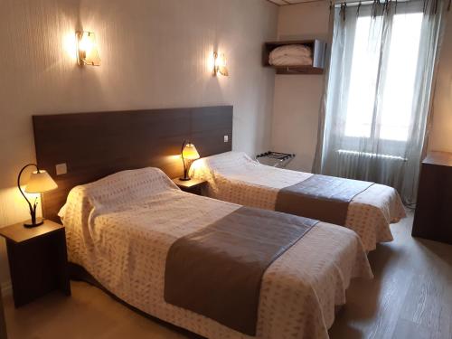 Habitación de hotel con 2 camas y 2 lámparas en Logis Hotels - Hôtel Le Boulevard en Mazamet